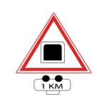 Pakistani cautionary road sign with a hazard symbol above a distance plate reading 1 KM inside a red-bordered triangle