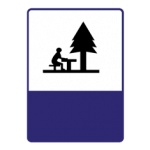 Pakistani informative road sign showing a person at a picnic table under a tree marking a picnic area
